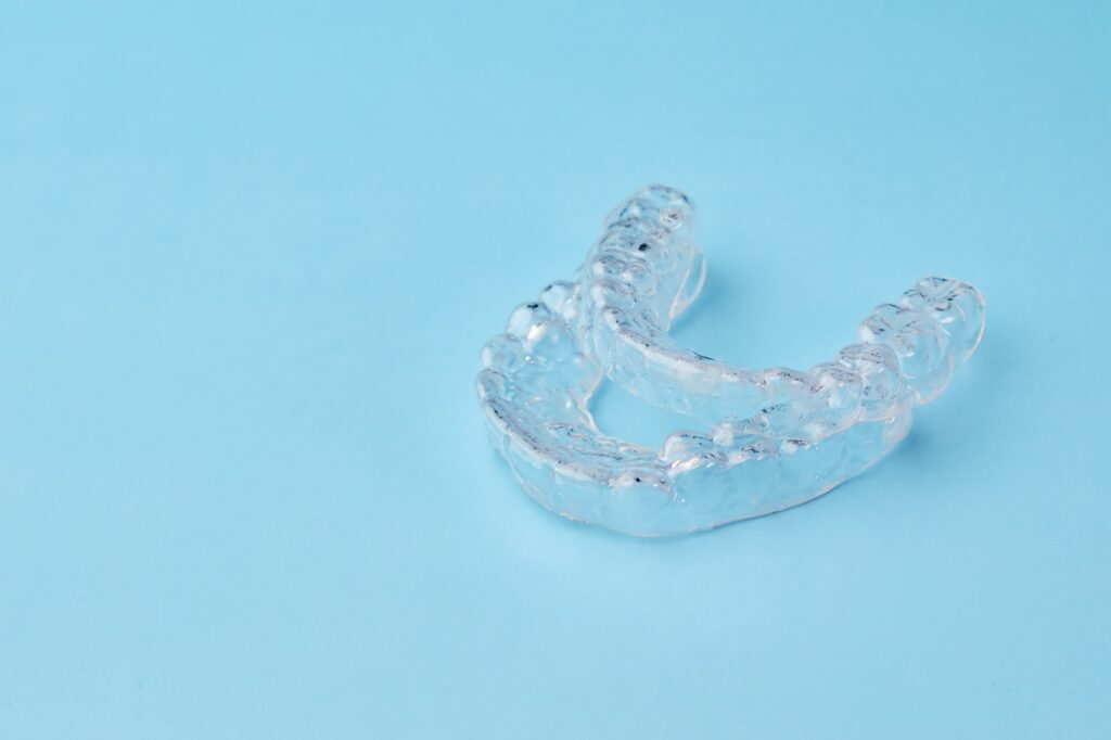 Close up invisible aligners on the blue background with copy space. Plastic braces dentistry